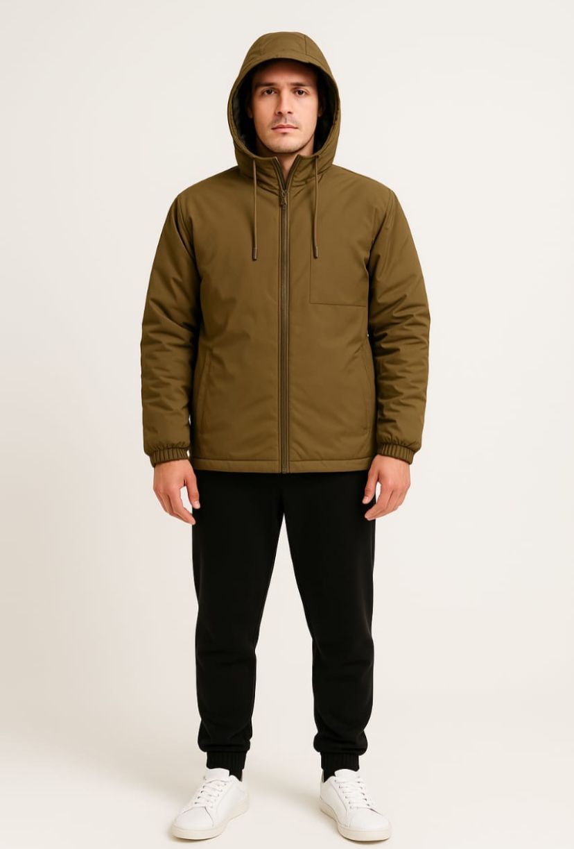 Hombre con una chaqueta de camuflaje con capucha y pantalones deportivos negros, de pie con las manos en los bolsillos.