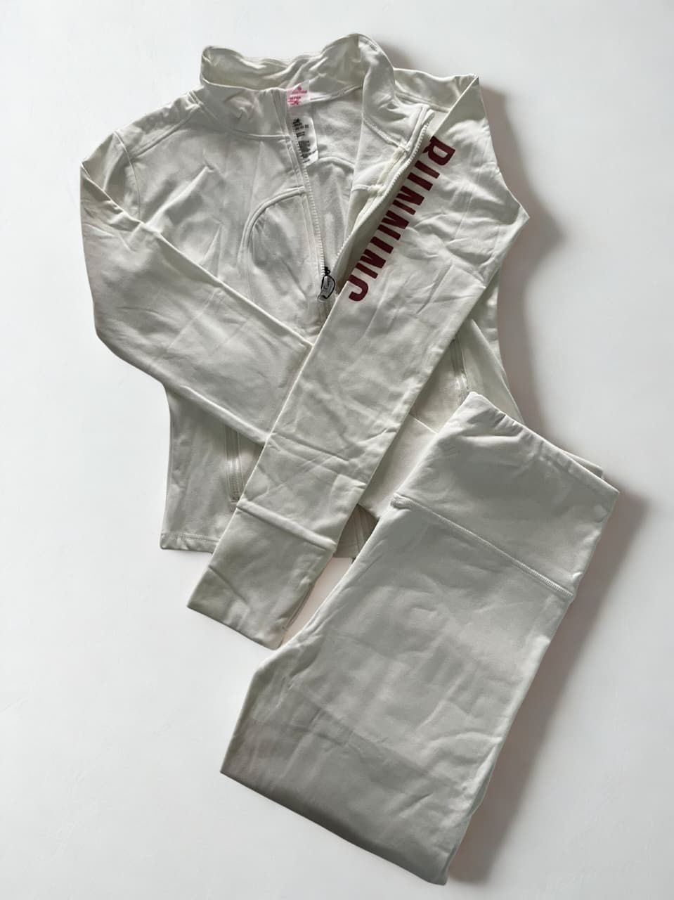 Una mujer vestida con ropa deportiva blanca se encuentra frente a un fondo blanco.