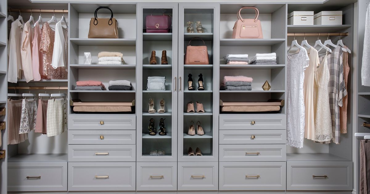 A well-organized gray walk-in closet with clothes, handbags, and accessories neatly arranged.