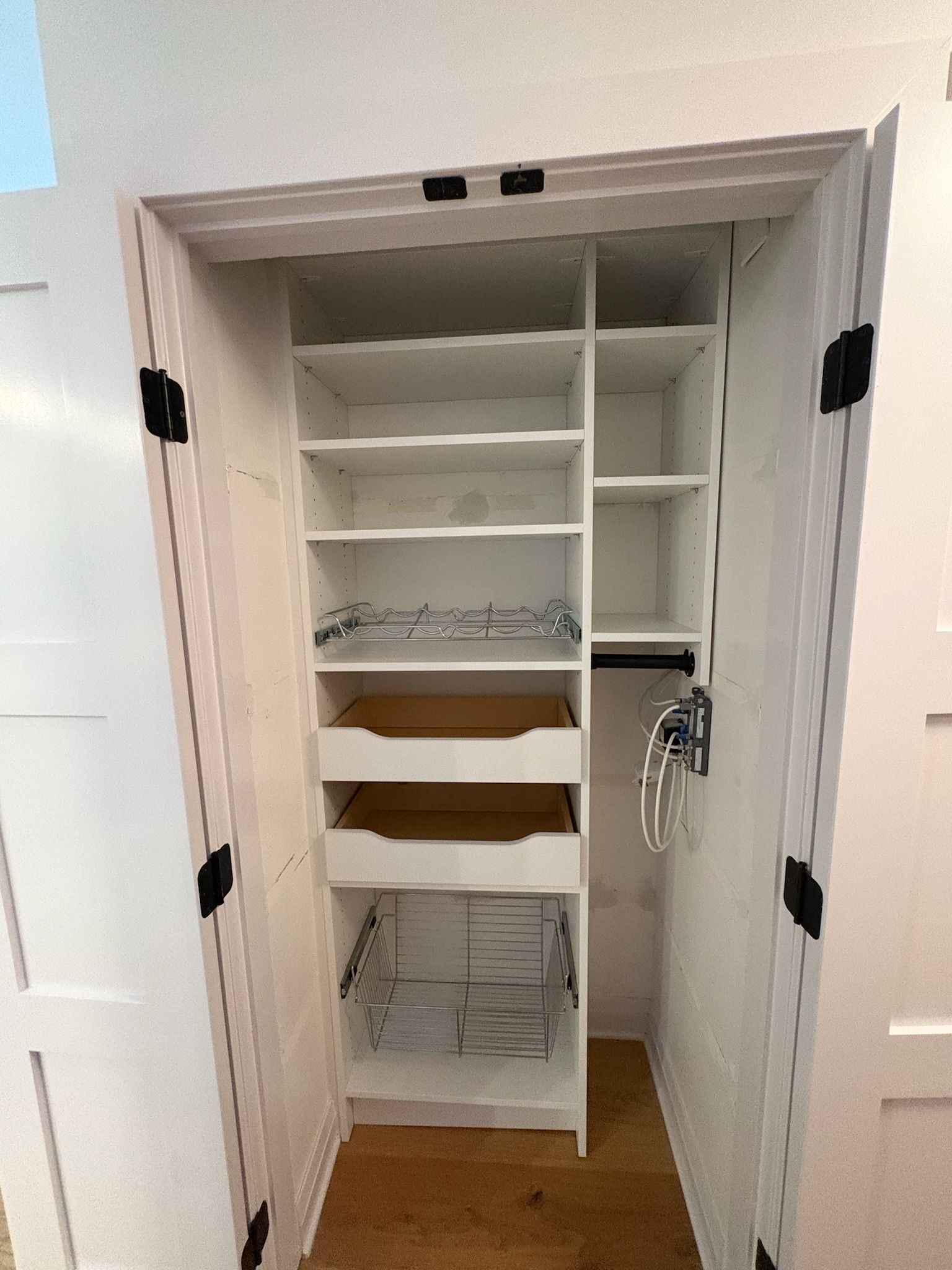 A white-walled closet with stacked shelves, two pull-out drawers, and a vertical side section with a hanging rod.