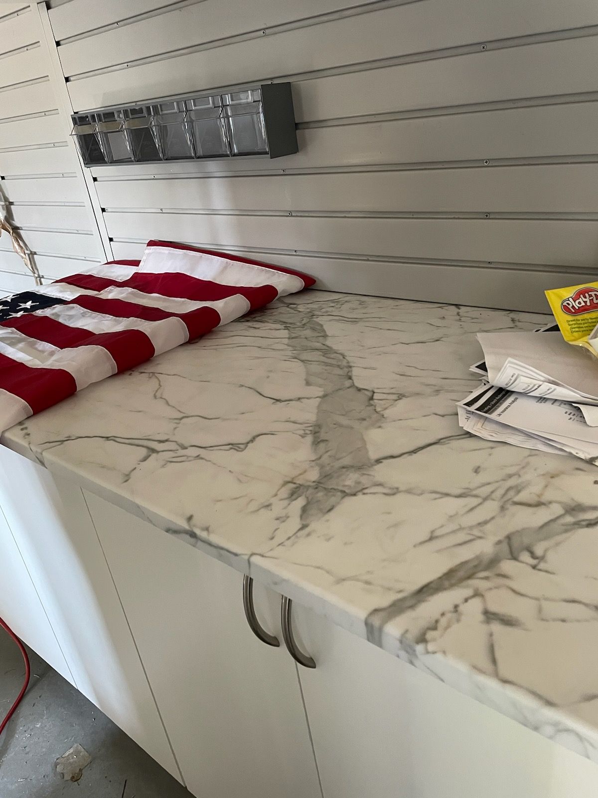 White marble countertop with a prominent crack, next to a red and white striped cloth in a storage area.