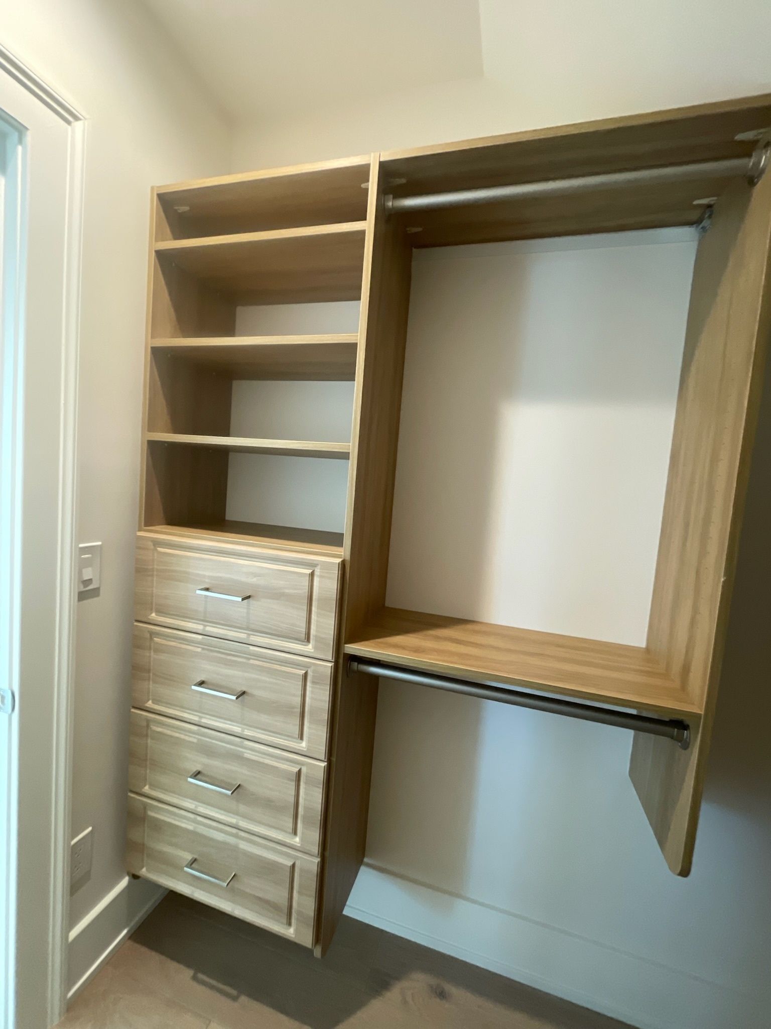 Light wood closet organizer with four drawers and overhead shelving, next to a hanging rod section.