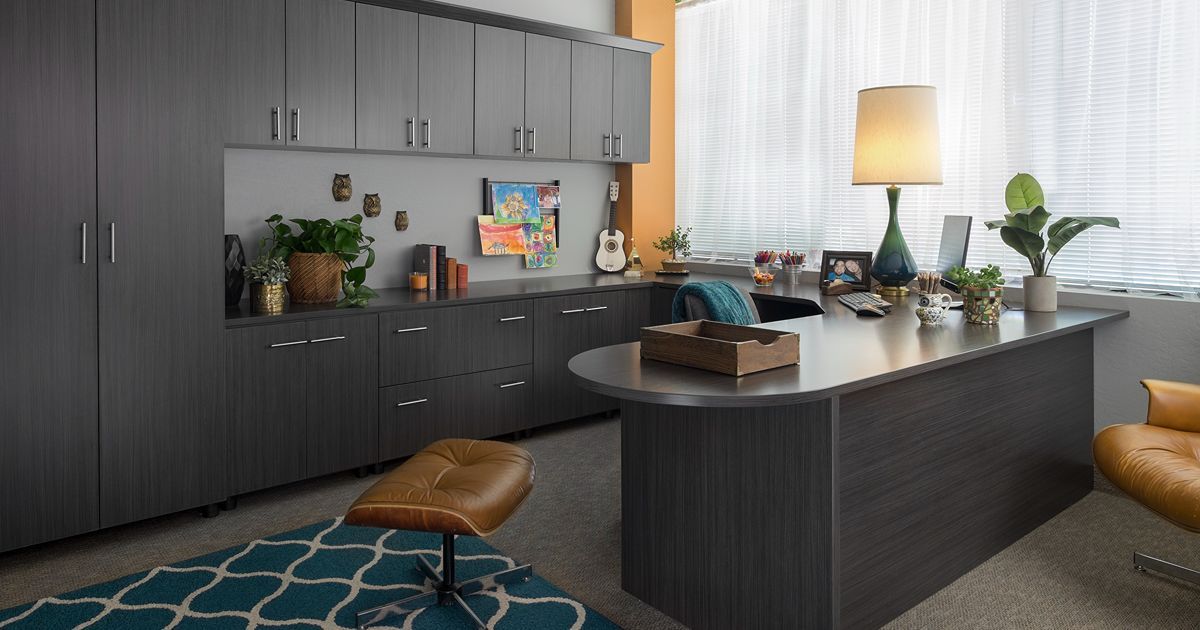 A modern, organized walk-in closet with white shelves, drawers, and hanging space, with dark brown accents and clothes.
