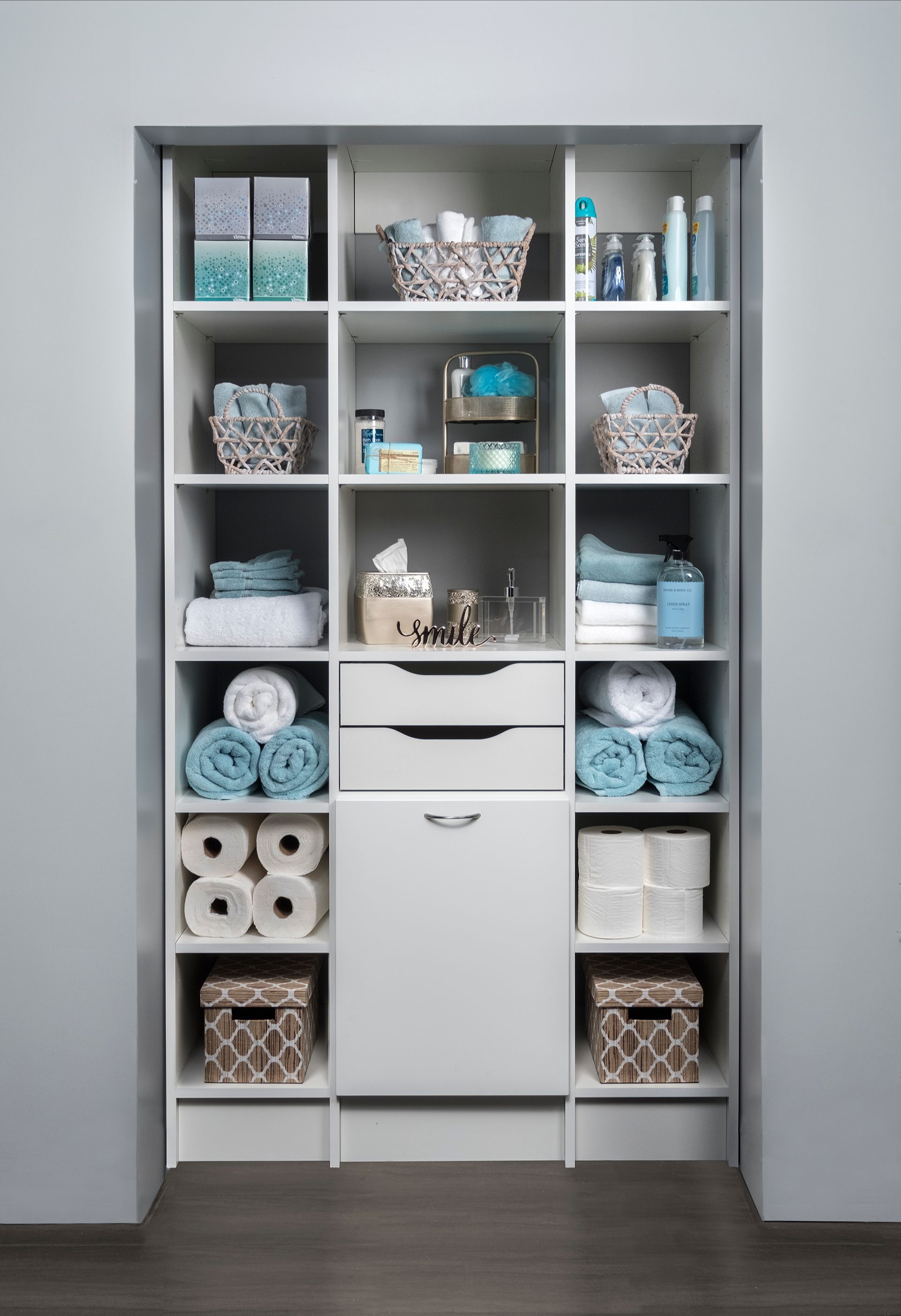 A well-organized walk-in closet with teal cabinetry and white shelving. Clothes hang, and decorative items are on display.