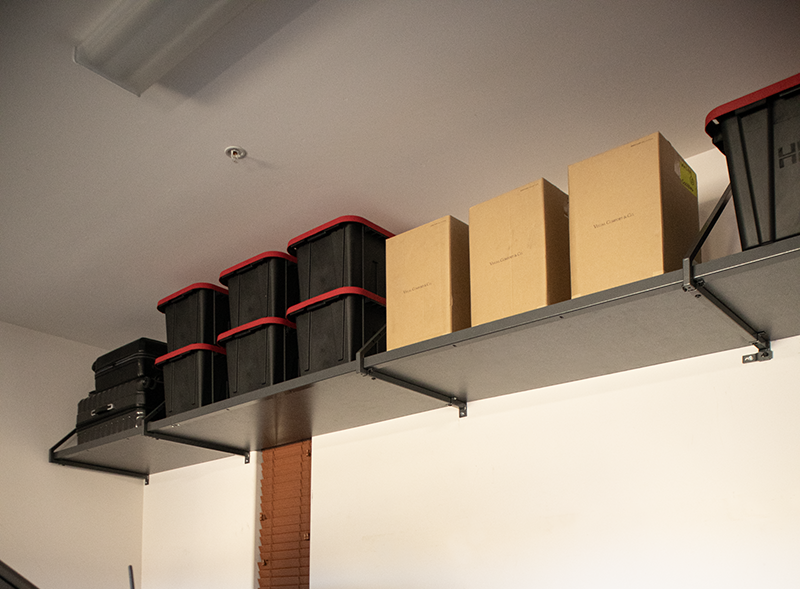 A modern, organized walk-in closet with white shelves, drawers, and hanging space, with dark brown accents and clothes.