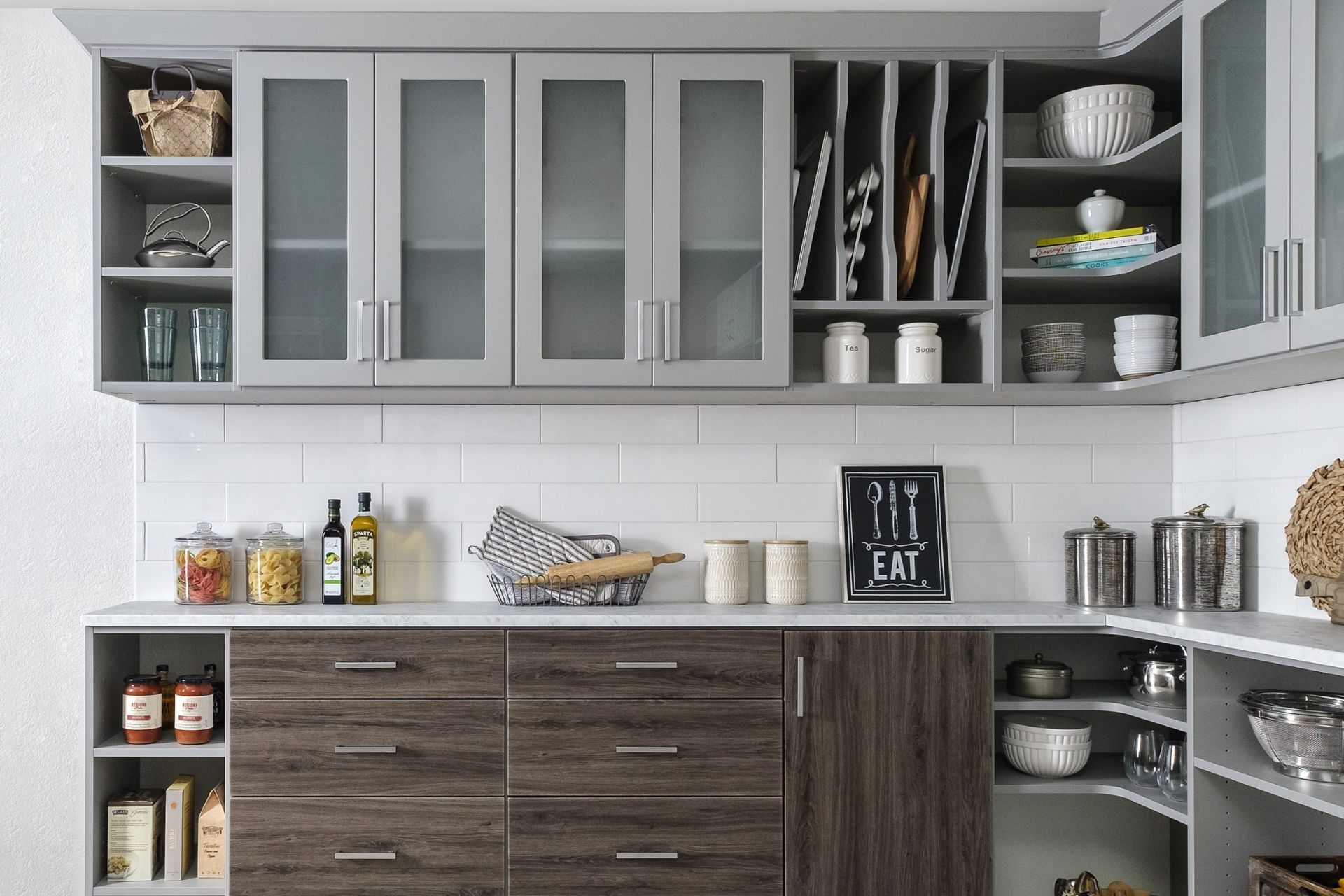 Gray walk-in closet with neatly organized clothing, including shirts, pants, and accessories. Neutral tones and a modern design are featured.