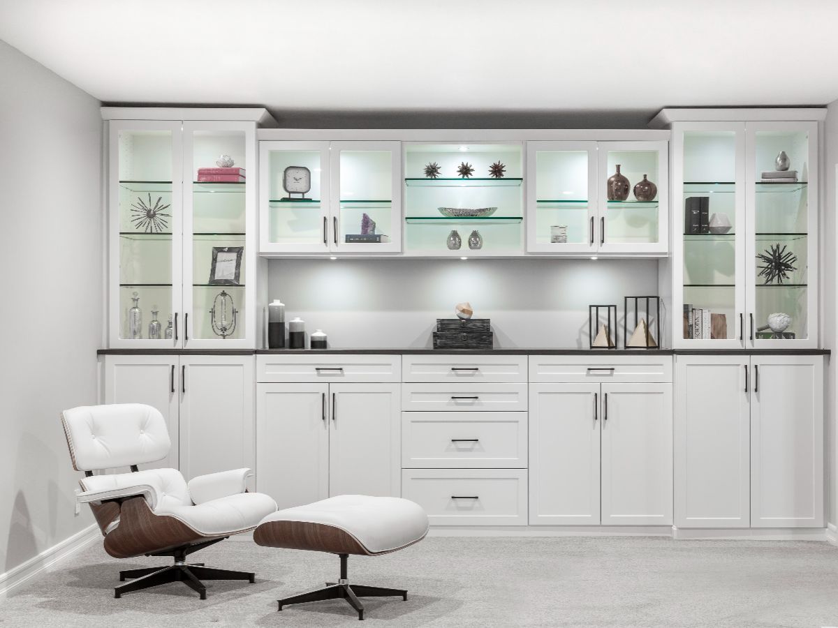 A modern, organized walk-in closet with white shelves, drawers, and hanging space, with dark brown accents and clothes.