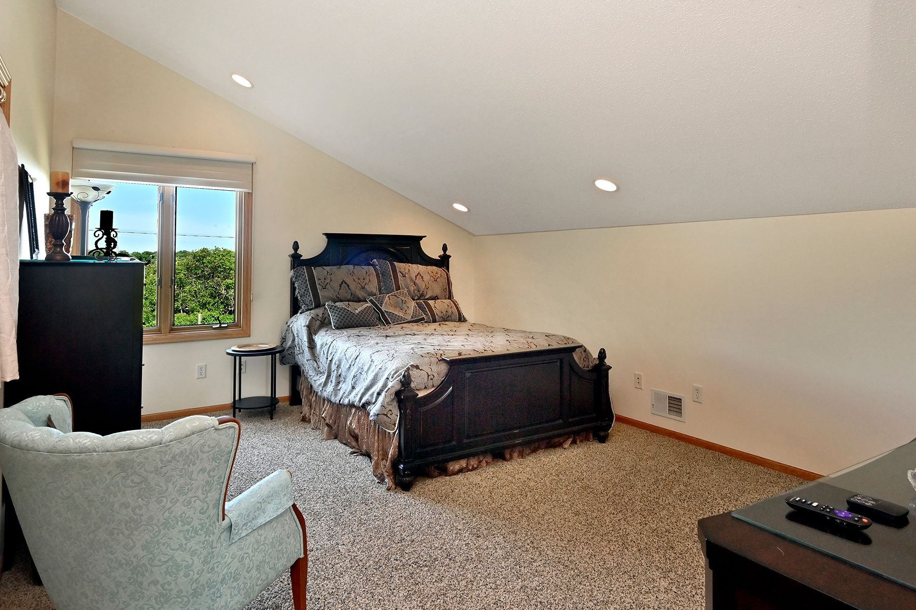 A bedroom with a large bed and a chair