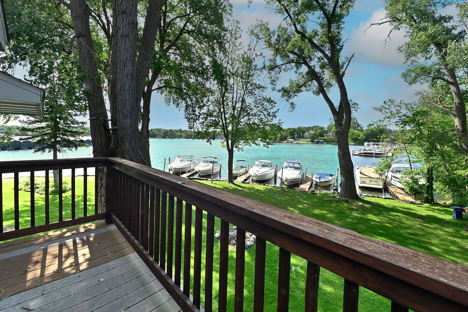 A view of a lake from a deck with a wooden railing