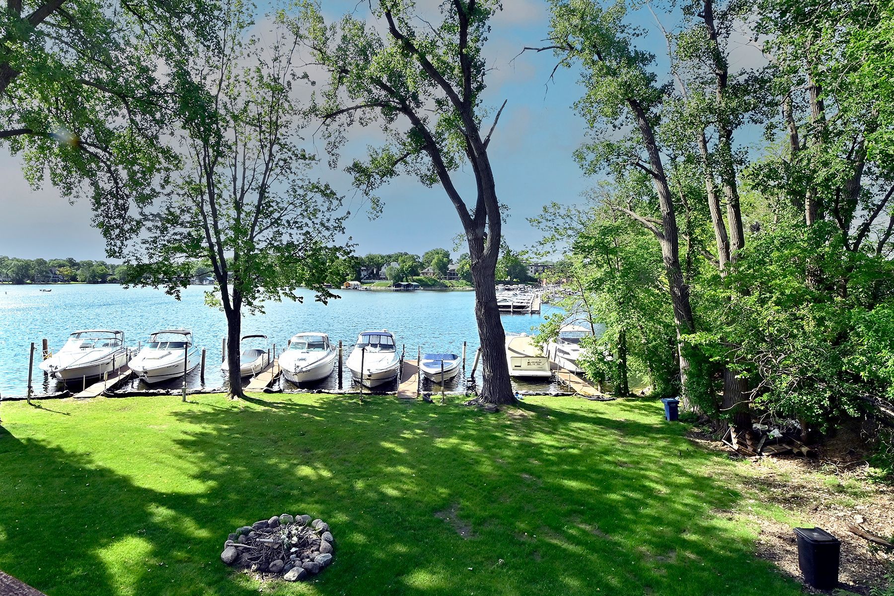 A lake with boats docked and a fire pit in the foreground