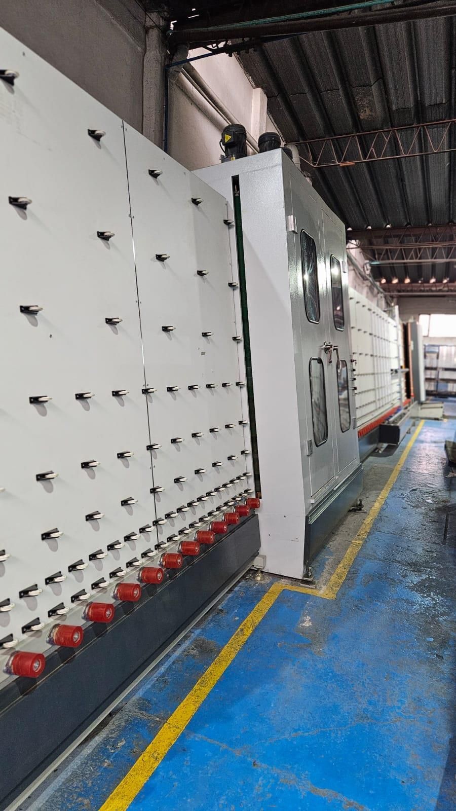 Gran máquina procesadora de vidrio industrial en un entorno de fábrica.