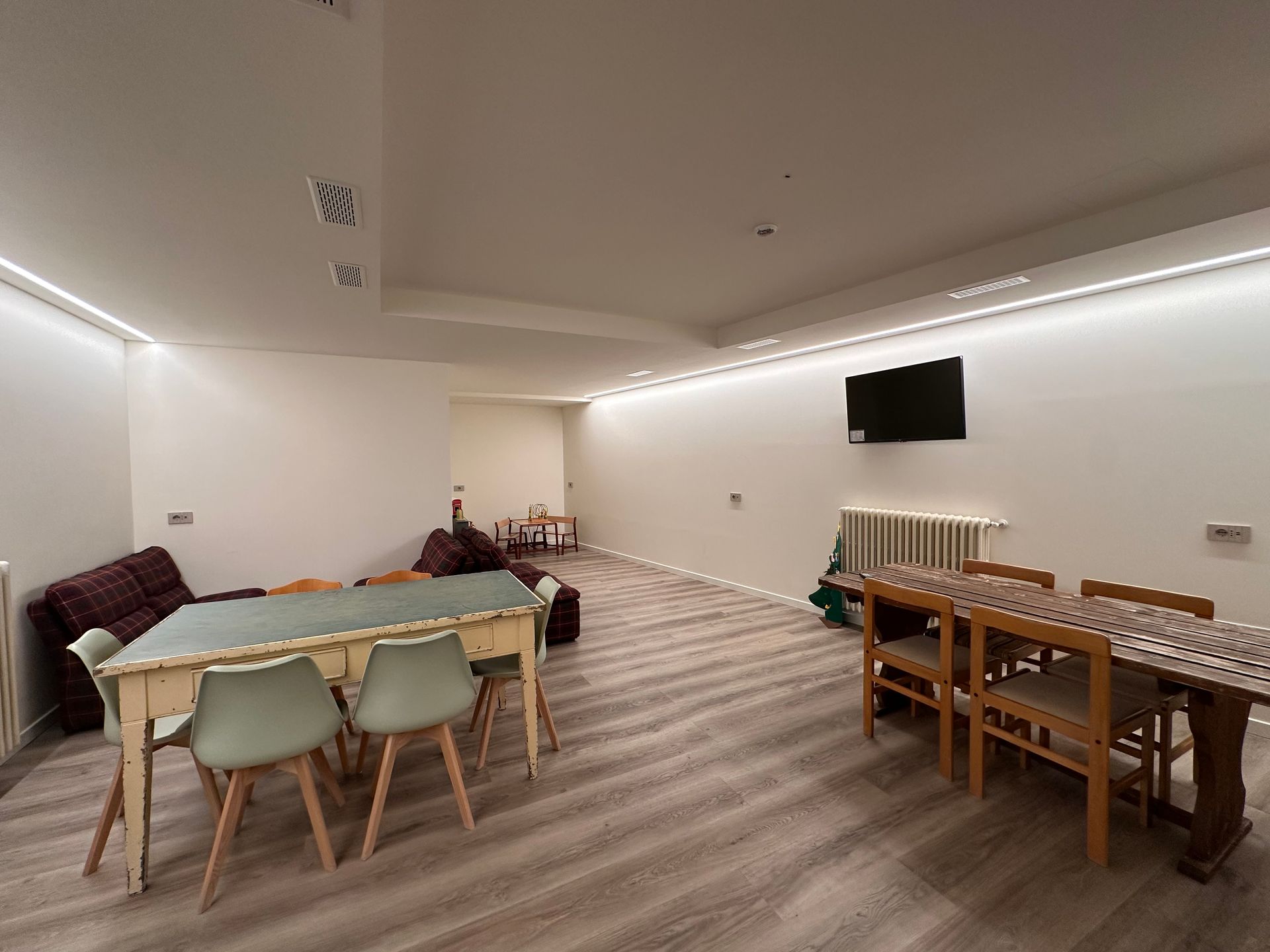 Camera spaziosa e ben illuminata, dotata di tavoli, sedie e TV. Dispone inoltre di un divano e di un termosifone contro il muro.