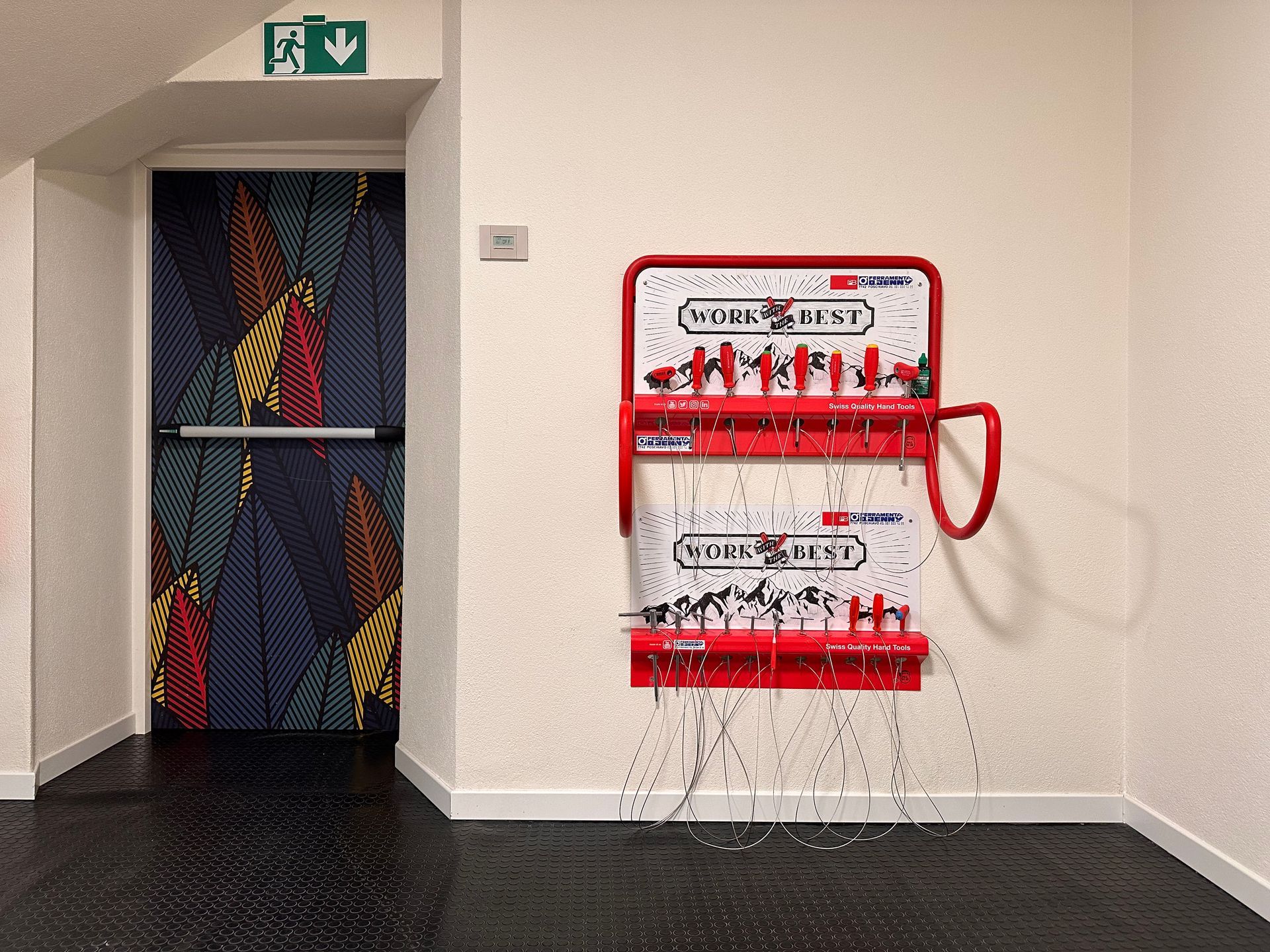 Stand per la riparazione di biciclette rosso e bianco in un corridoio accanto a una porta decorata.