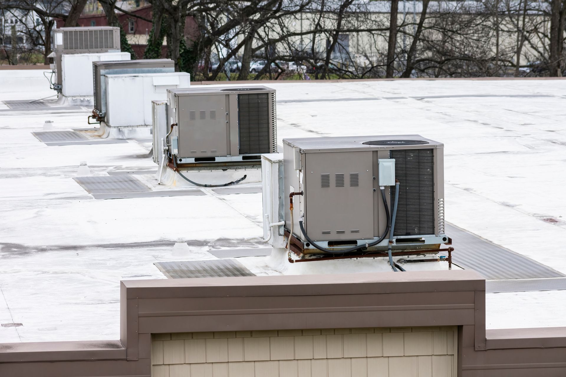 A row of air conditioners are sitting on top of a building.
