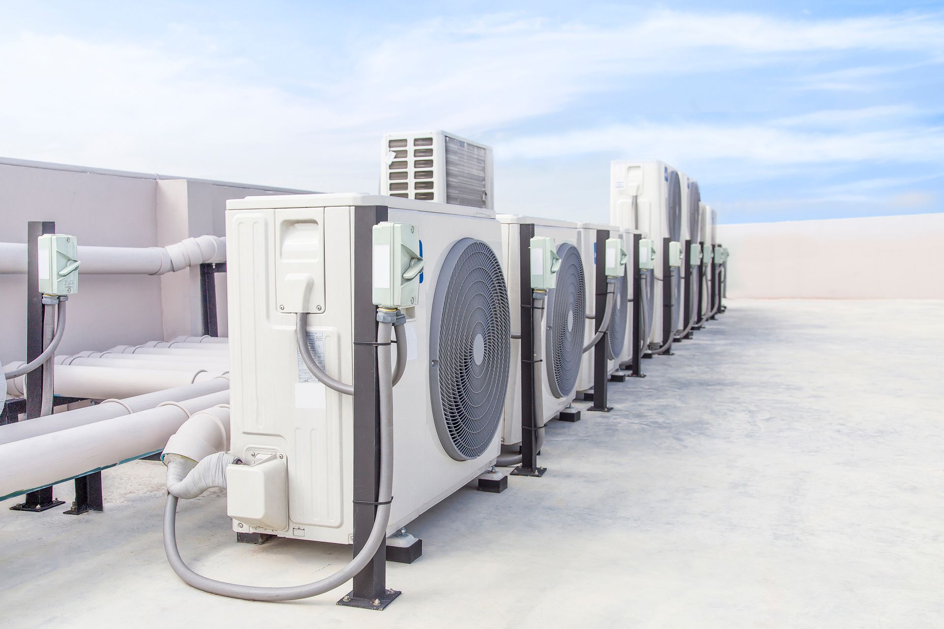 A row of air conditioners on the roof of a building.