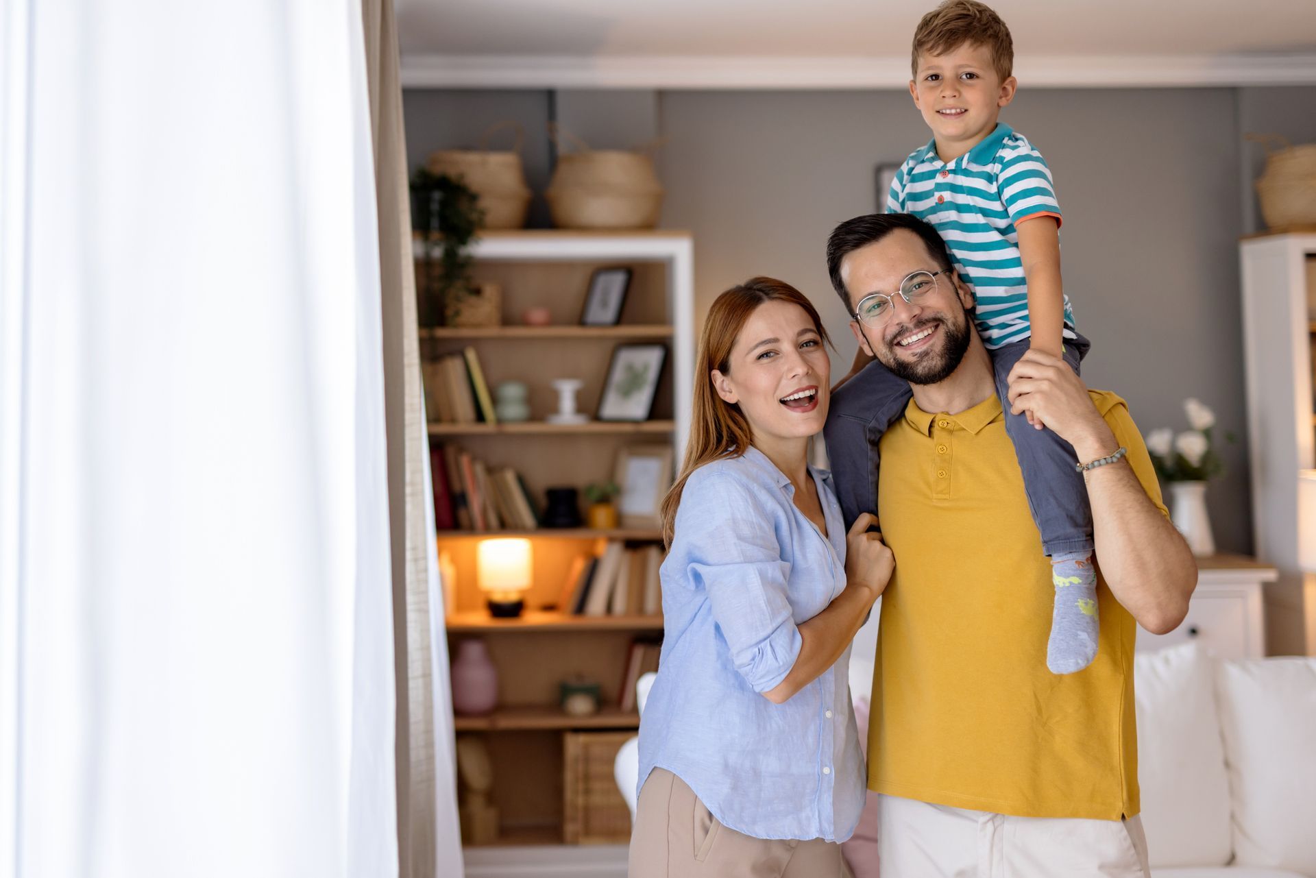 A man is standing on a ladder installing an air conditioner on the side of a building.