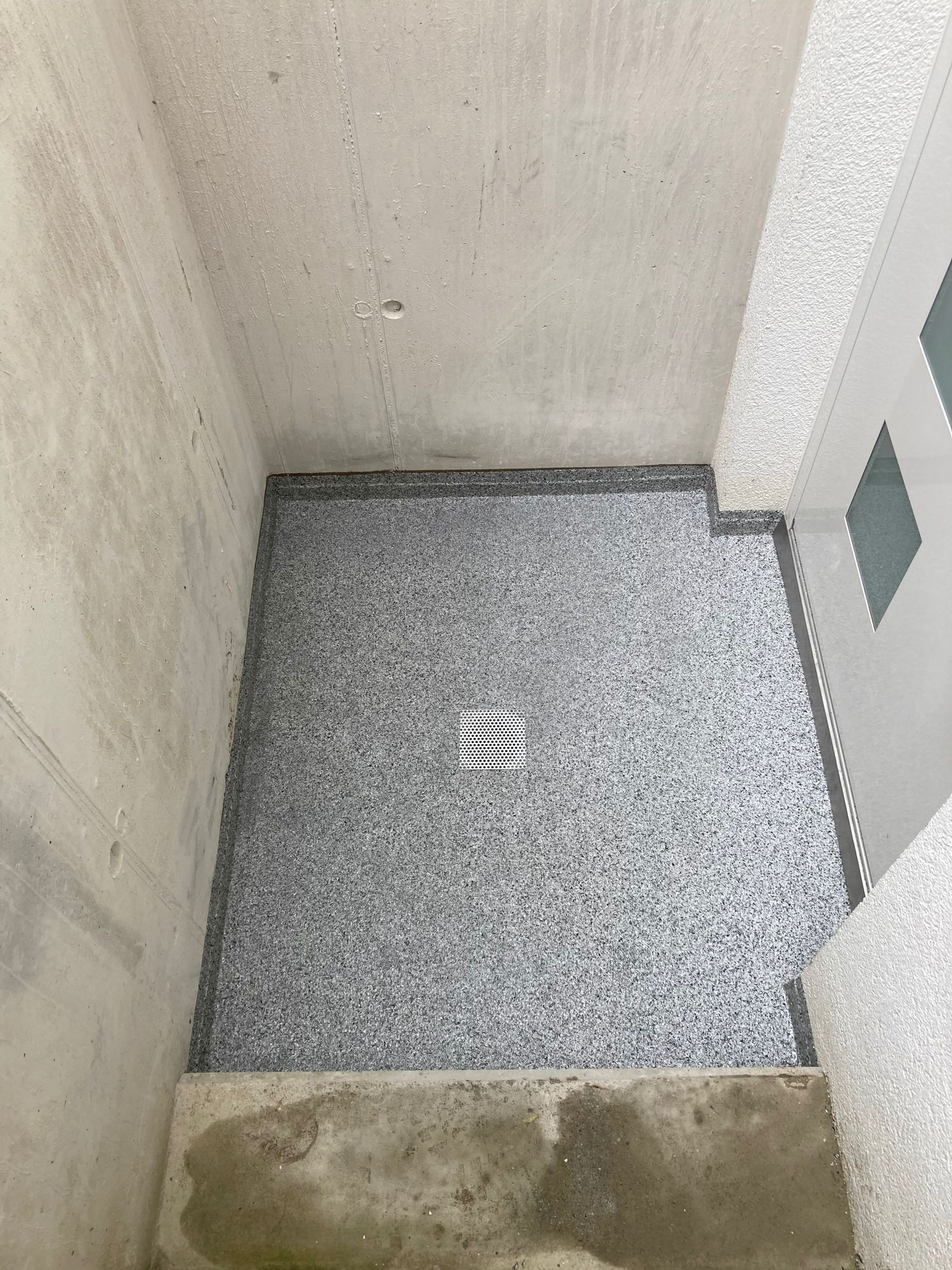 ein Raum mit einem grauen Boden und einer weißen Tür