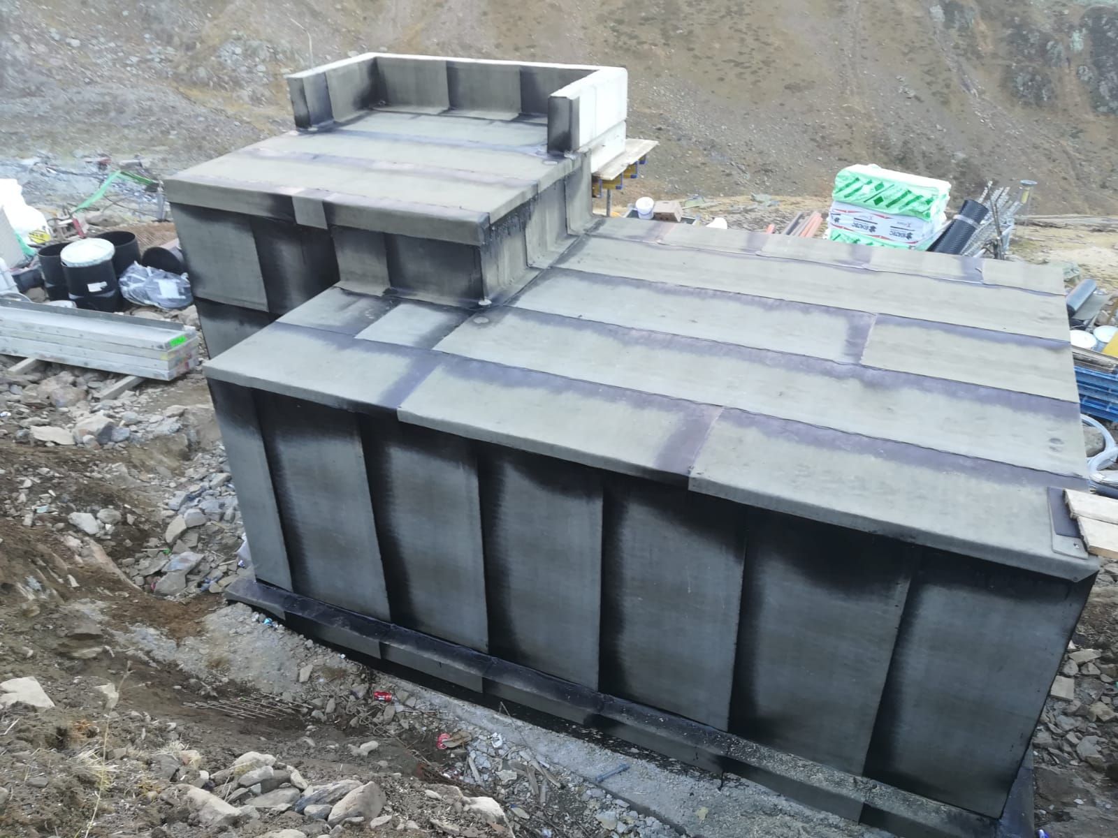 ein großer schwarzer Betonblock steht auf einem felsigen Hügel