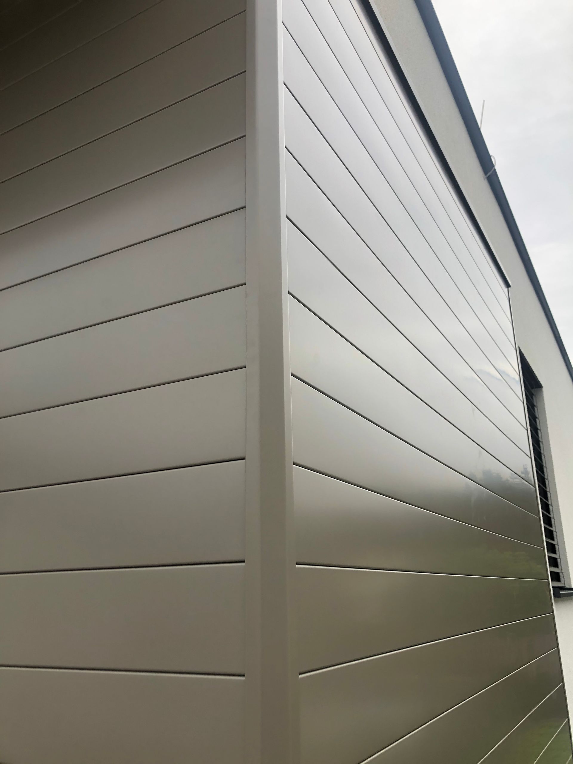 die Seite eines Gebäudes mit grauen Platten und einem Fenster