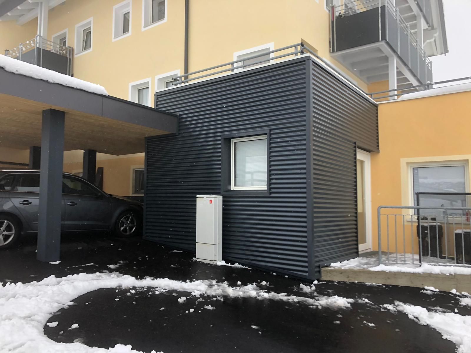 ein Auto steht unter einer Garage in der Nähe eines gelben Gebäudes