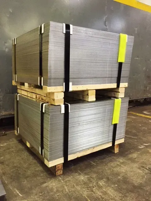 Two pallets of metal sheets are stacked on top of each other.