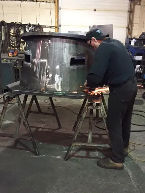 A man is grinding a piece of metal in a garage