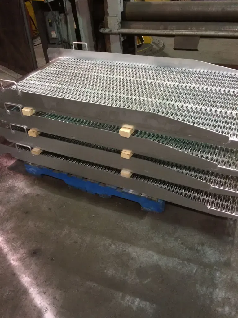 A stainless steel conveyor belt is stacked on top of each other on a blue pallet.