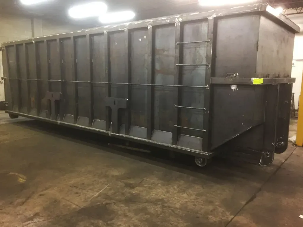 A large dumpster is sitting in a garage.