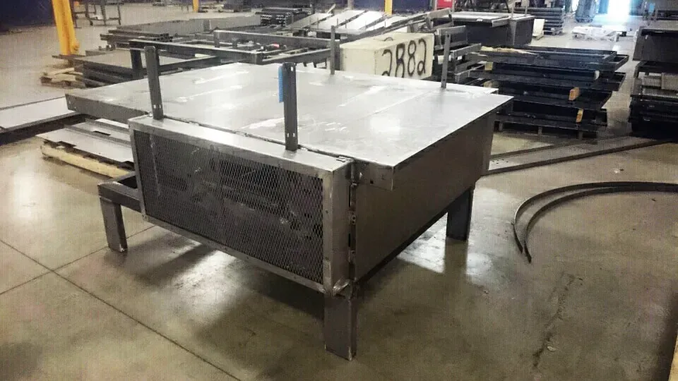 A large metal box is sitting on top of a concrete floor in a factory.