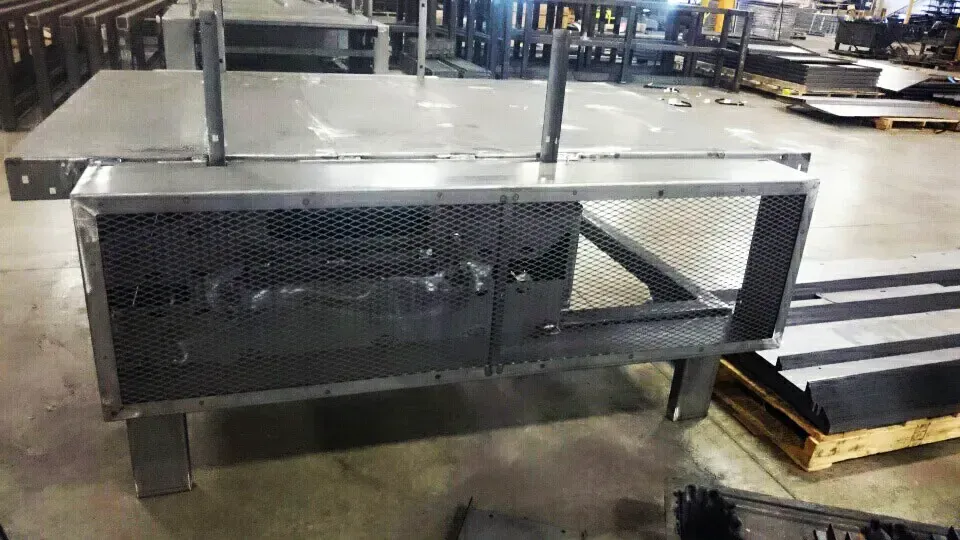 A large metal box is sitting on top of a concrete floor in a factory.