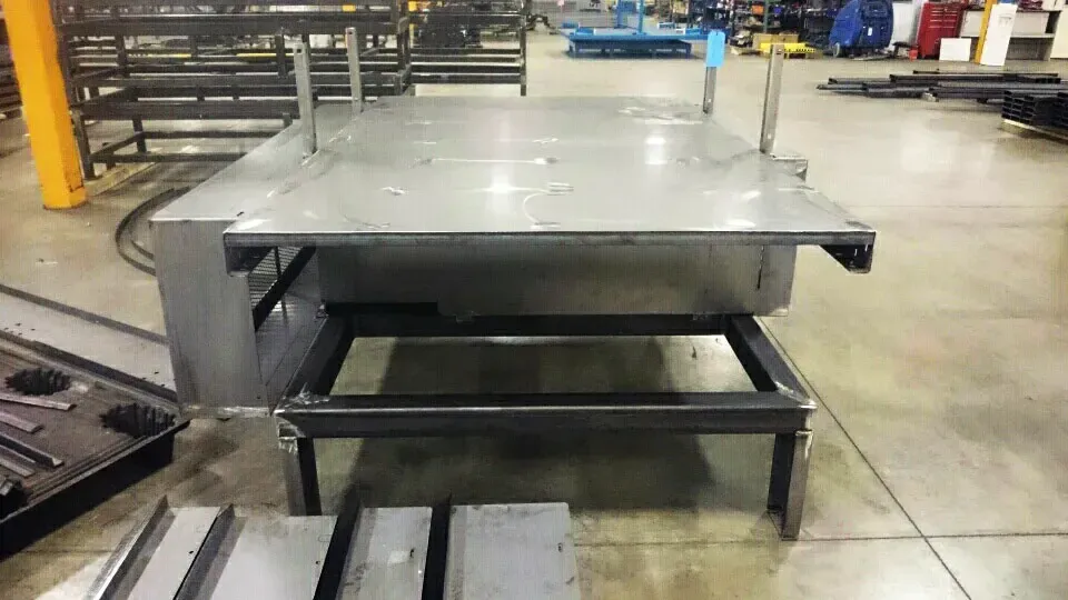 A metal table is sitting on top of a concrete floor in a factory.