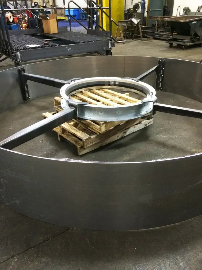 A large metal ring is sitting on top of a wooden pallet.