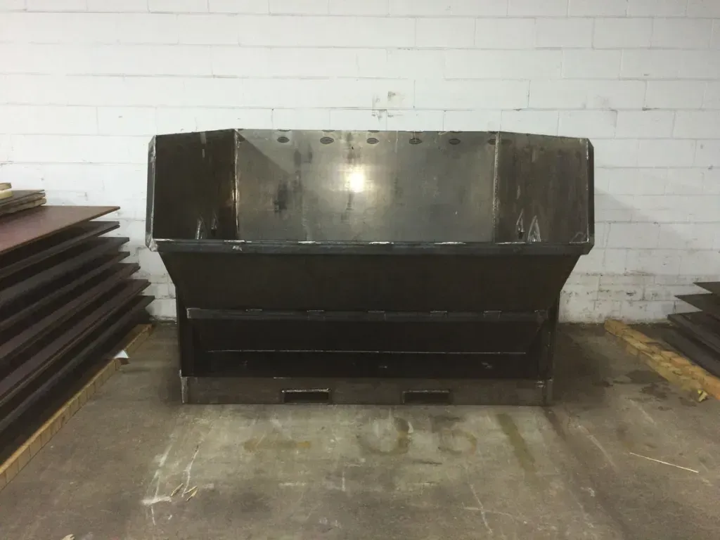 A large black dumpster is sitting in a warehouse