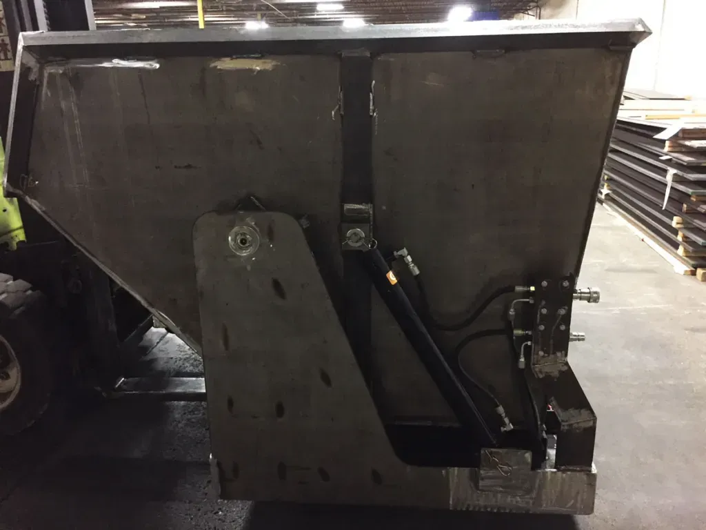 A dumpster is sitting in a warehouse next to a forklift