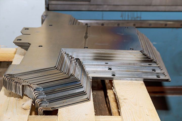 A bunch of metal pieces are stacked on top of each other on a wooden pallet.