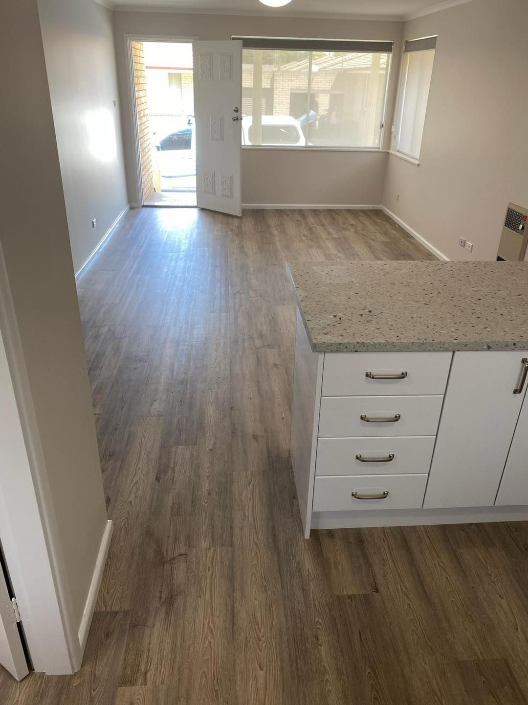 A Kitchen With A Wooden Floor , White Cabinets And A Granite Counter Top — Cabonne Carpets In Molong, NSW