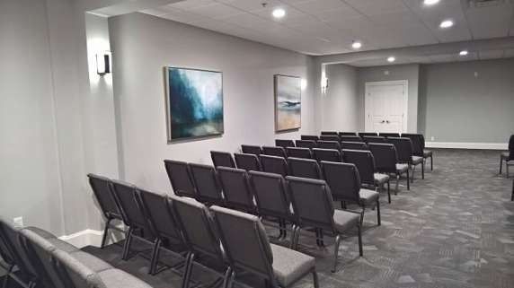 Rows of chairs face a wall with artwork in a gray-walled room.