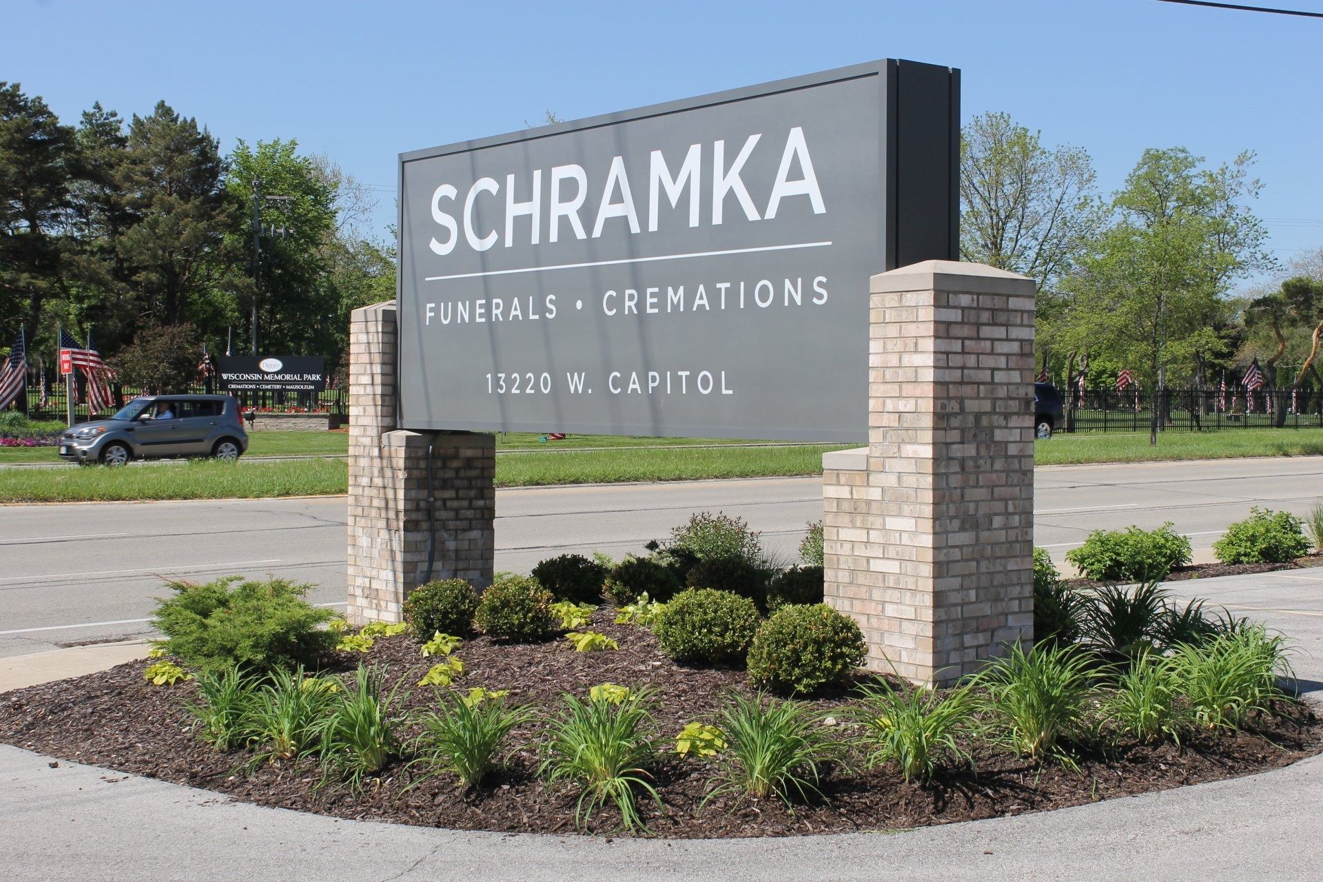 Sign for Schramka Funeral Home with brick columns, text on gray background. Address 11020 W. Capitol.