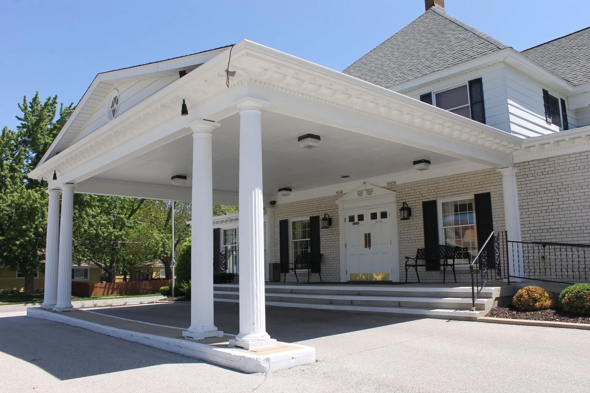 White building with a portico supported by columns, likely a funeral home.