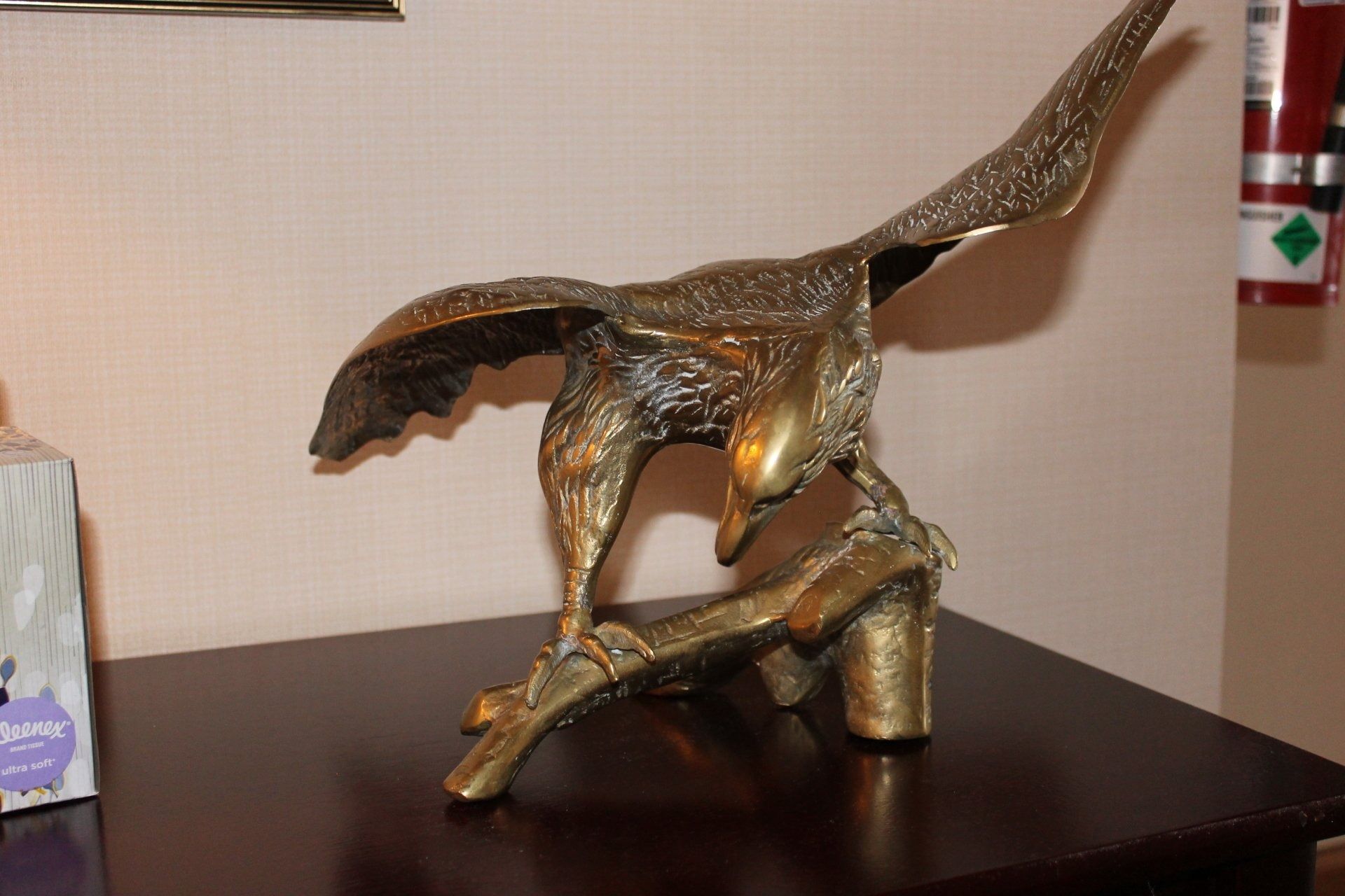 Brass eagle statue perched on a branch, wings spread, looking down.
