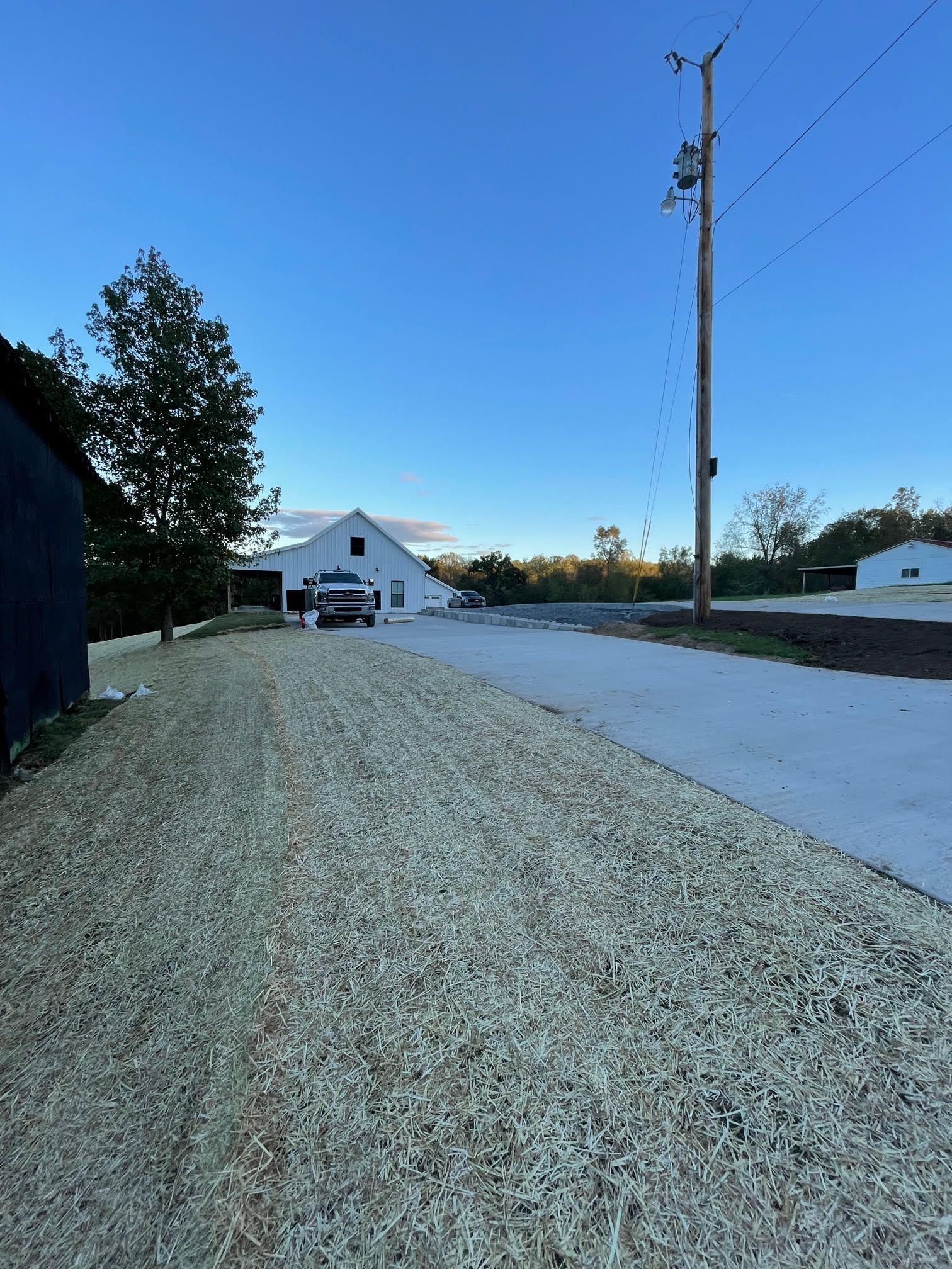 A white truck is parked on the side of a gravel road.