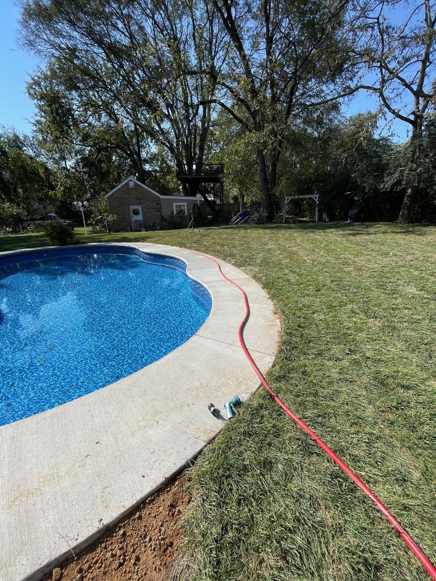 A hose is connected to a swimming pool in a backyard.
