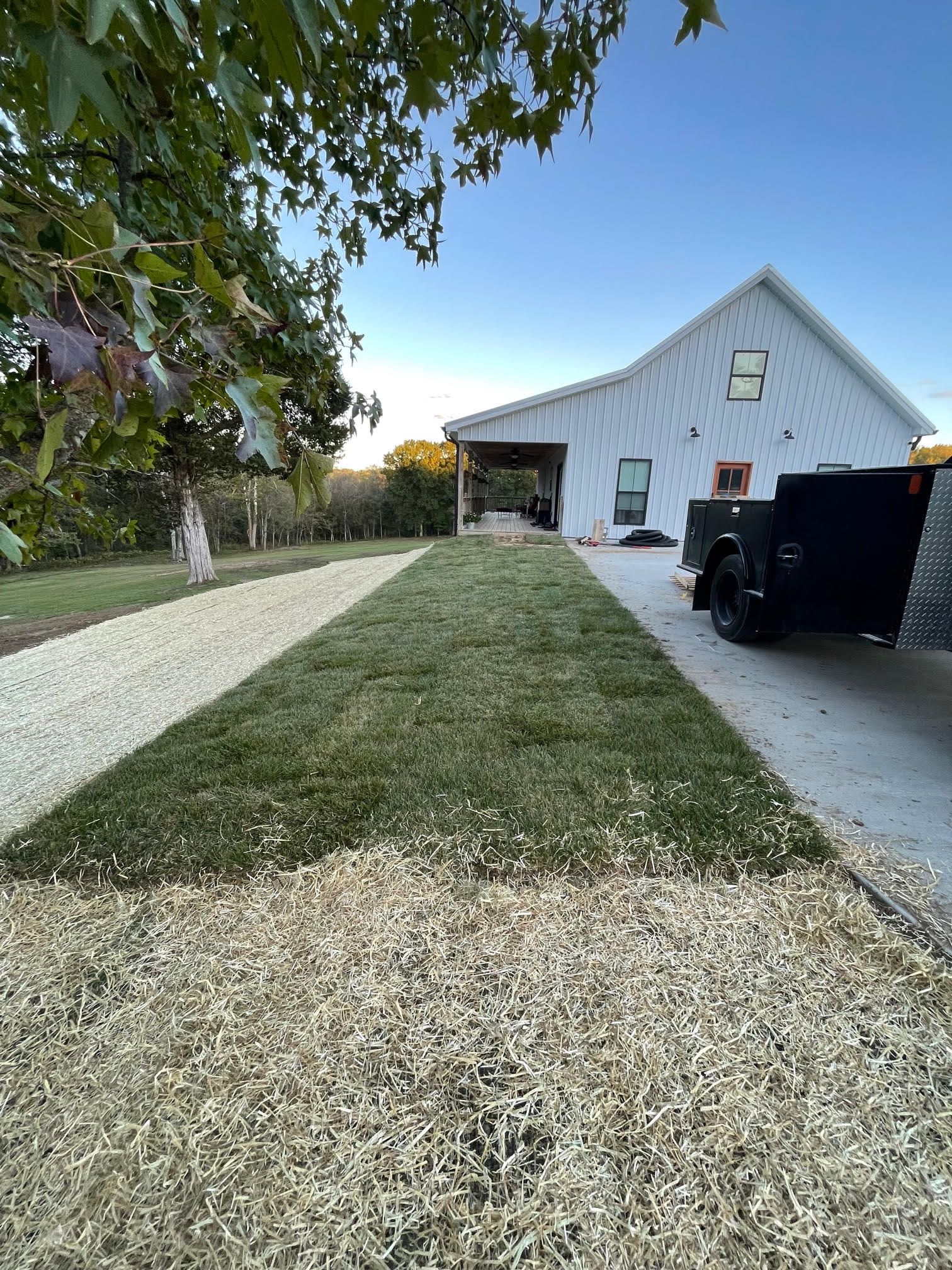 A white house with a gravel driveway and a truck parked in front of it.