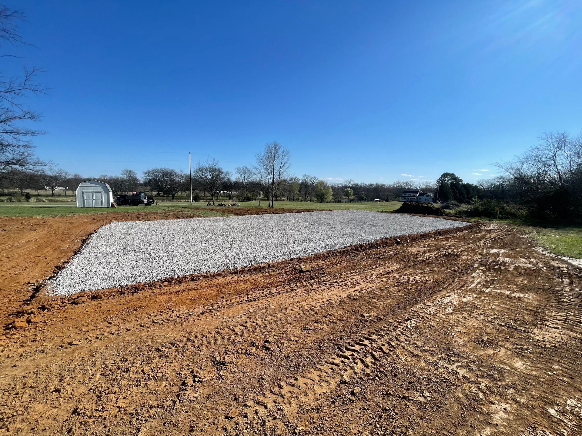 A gravel path leading to a house in the middle of a grassy field.