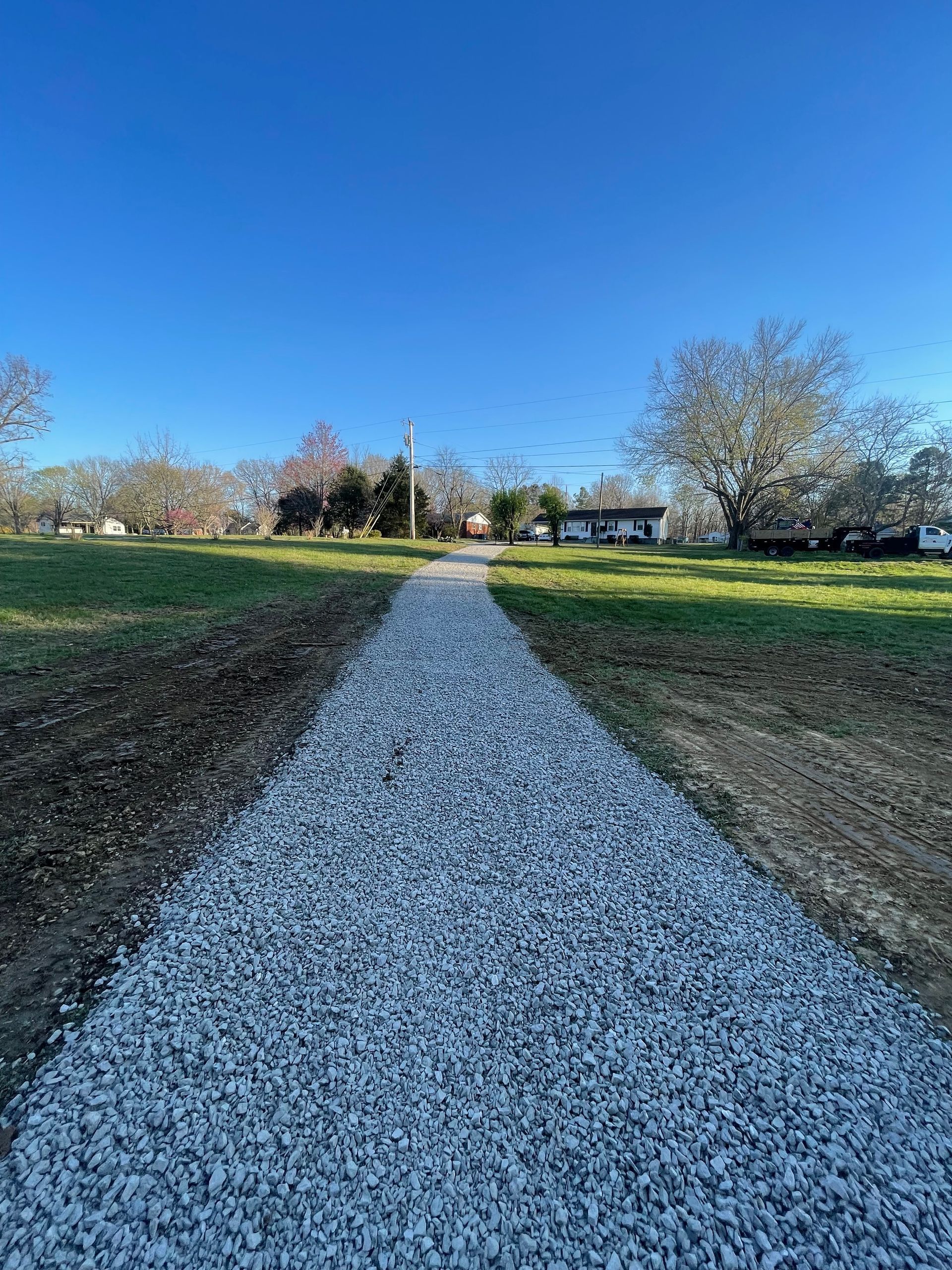 A gravel path leads toward buildings under a bright blue sky.