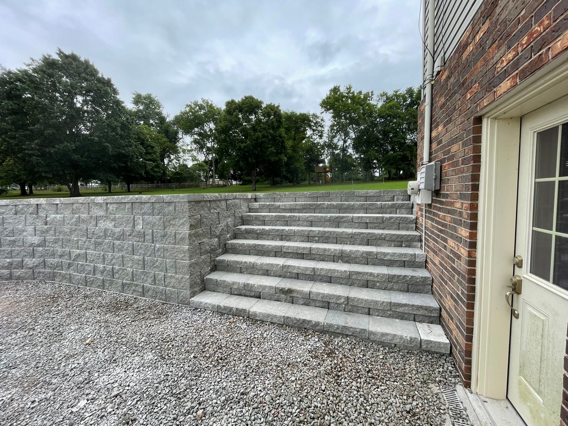 A stone walkway leading to a house with a porch.