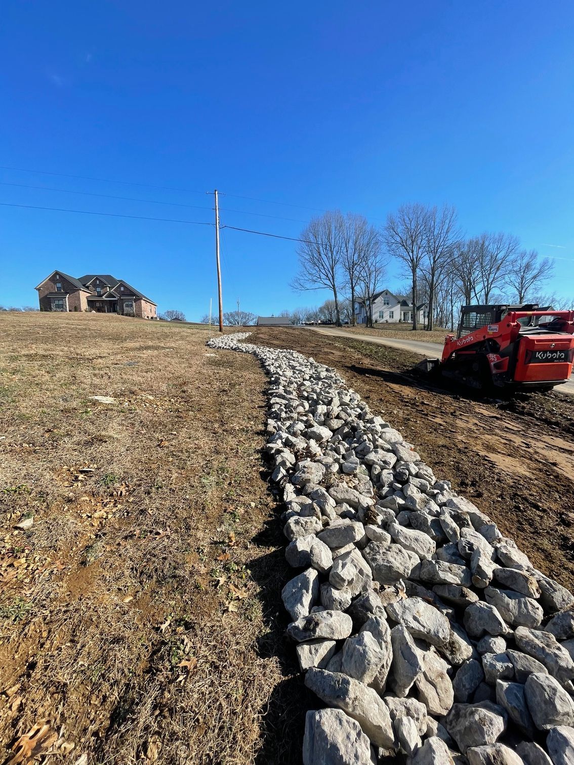 A red truck is driving down a dirt road next to a pile of rocks.