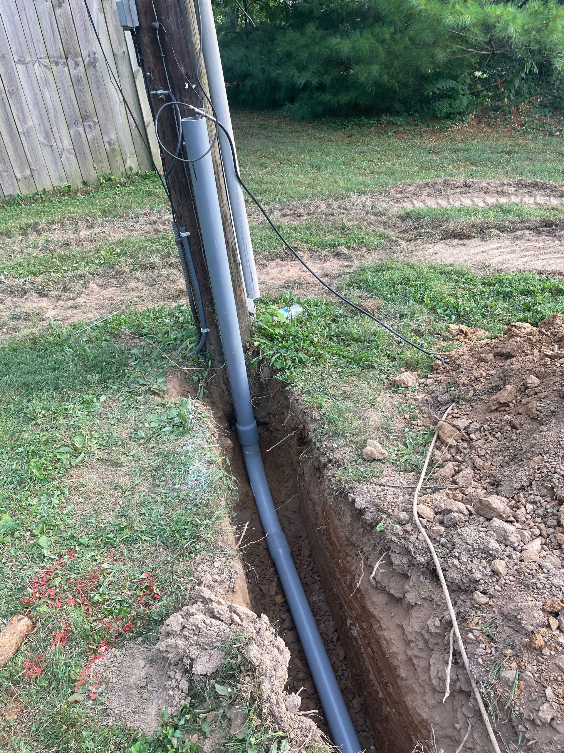 A pipe is being installed in the ground next to a telephone pole.