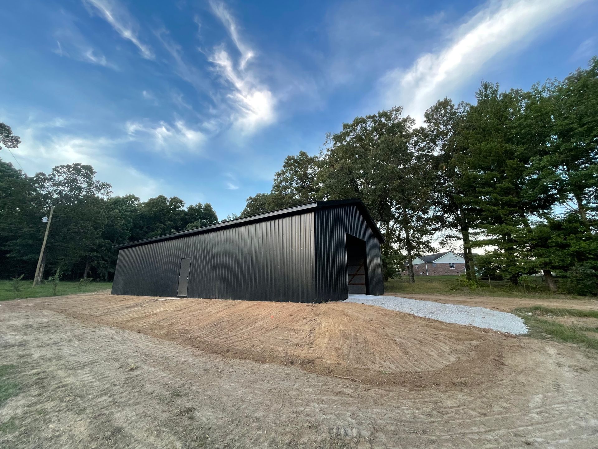 A black metal building is sitting in the middle of a dirt field.