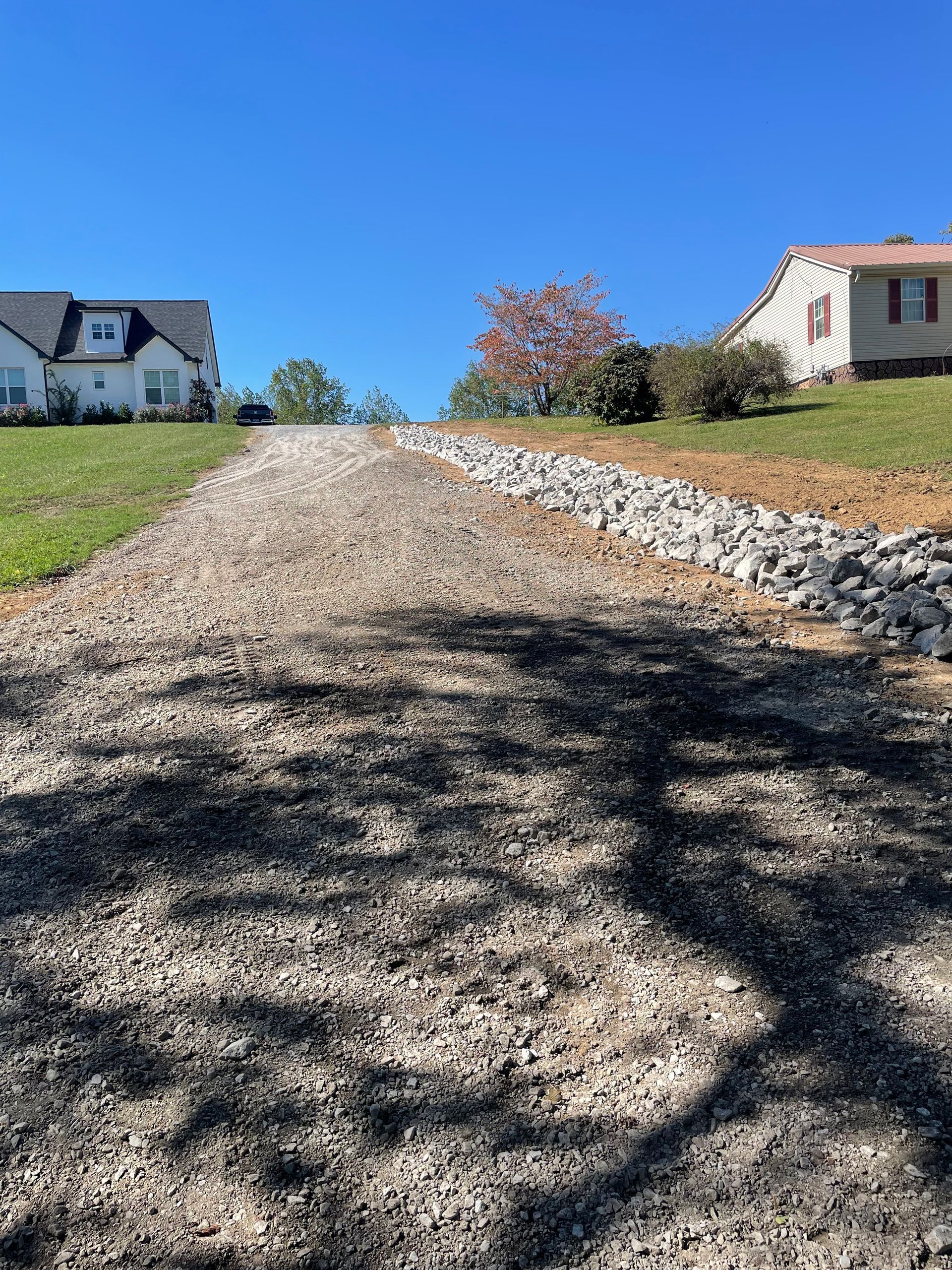 A gravel driveway leading to a house on a hill.
